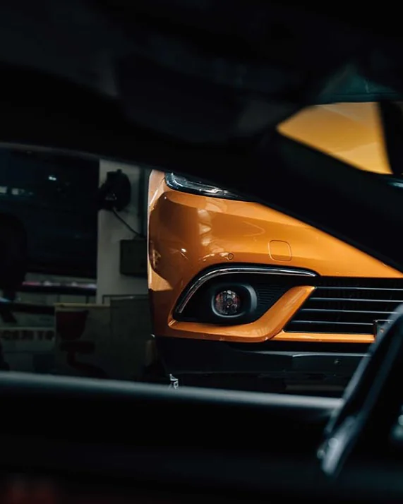 Front eines orangefarbenen Autos mit Scheinwerfer im Autohaus - Autoscout-API-Anbindung